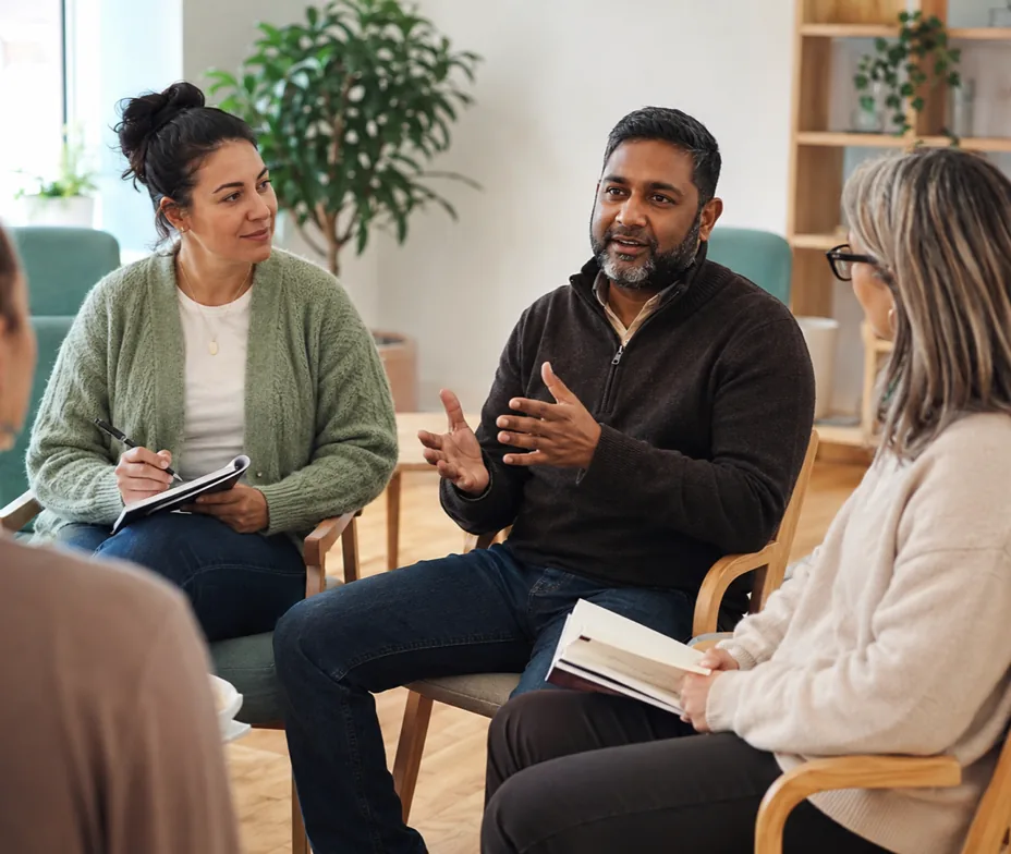 A trainer leads a calm seated discussion between colleagues during learning disability and autism training.